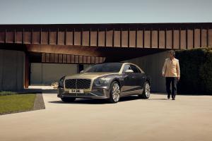 Side profile of the new hybrid Bentley Flying Spur in Tourmaline Green driving in an urban environment