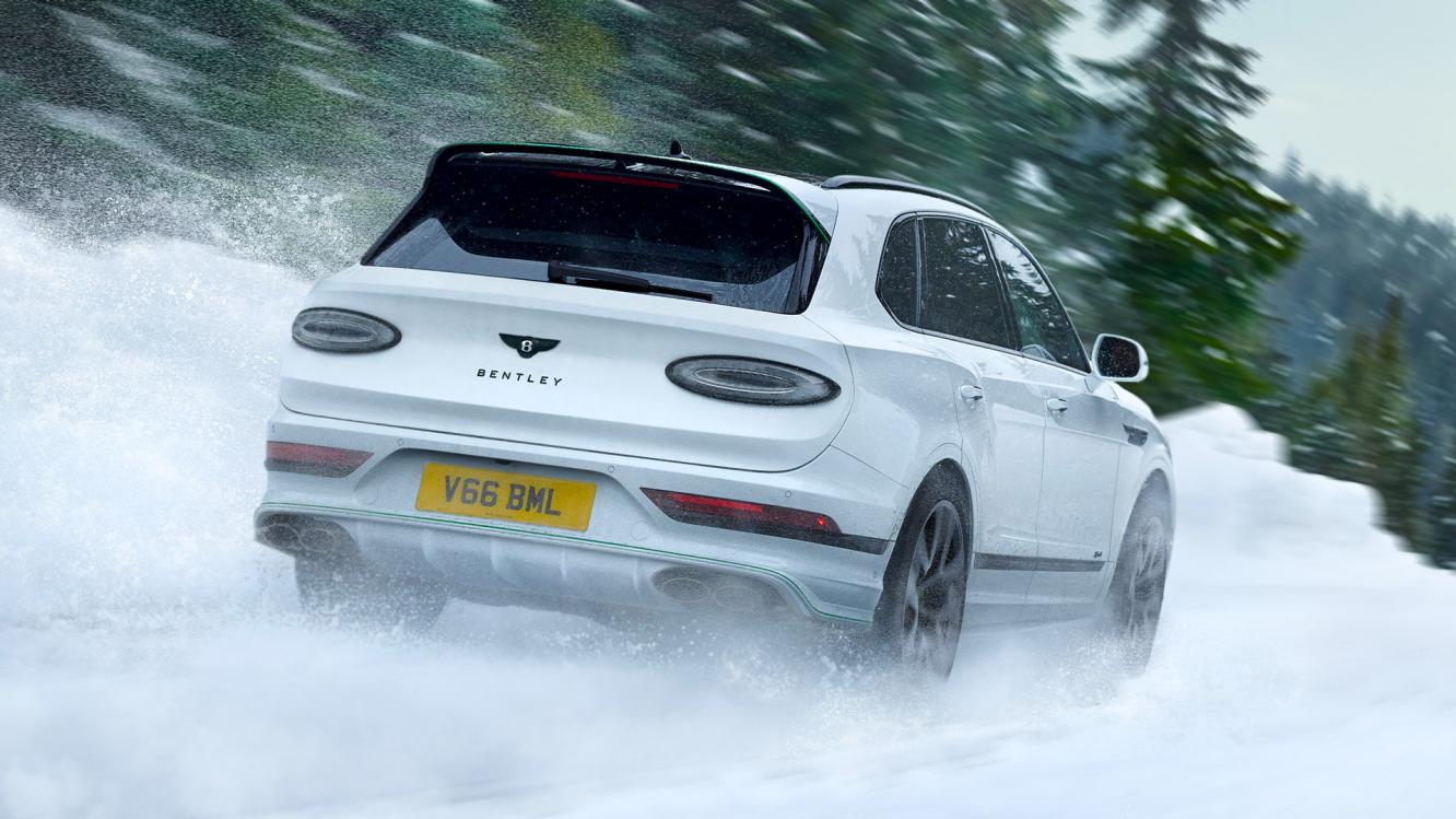 New Bentayga Speed in Snow Quartz by Mulliner exterior paint with the Bentayga Styling Specification and 23" Directional Wheels driving in a snowy enviornment.