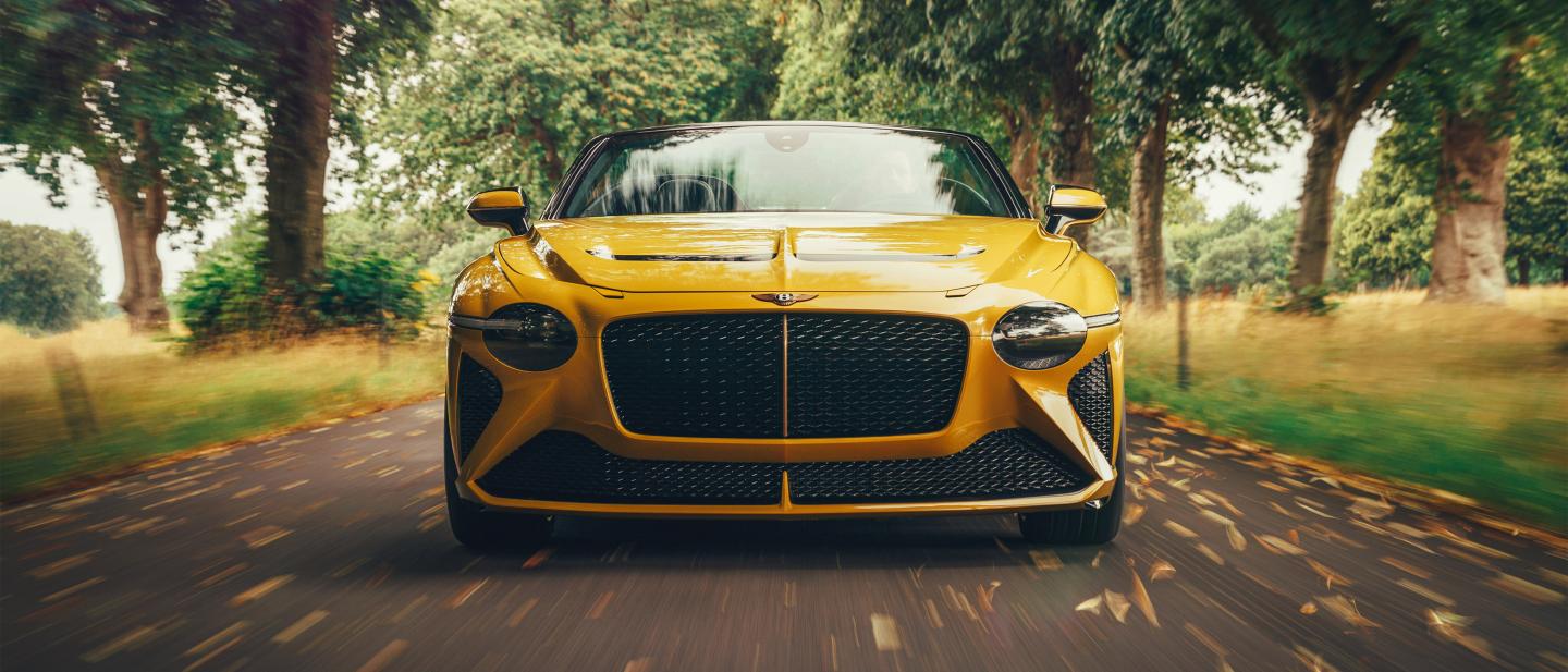 Bentley Bacalar with roof down in Chrome Yellow colour featuring 22 inch directional allow wheels and matt black front matrix grille with matrix wing vents in view