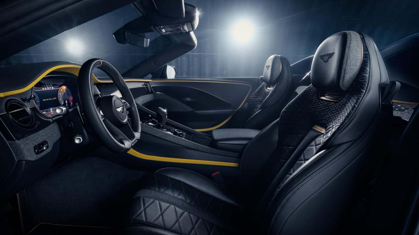 Interior view of Bentley Bacalar featuring Beluga hide - contrasted by Chrome Yellow hide over looking passenger side with tri spoke, indented steering wheel in view.